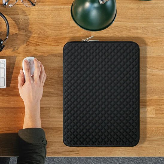 housse pour ordinateur posee sur bureau proche main tenant souris pour travailler